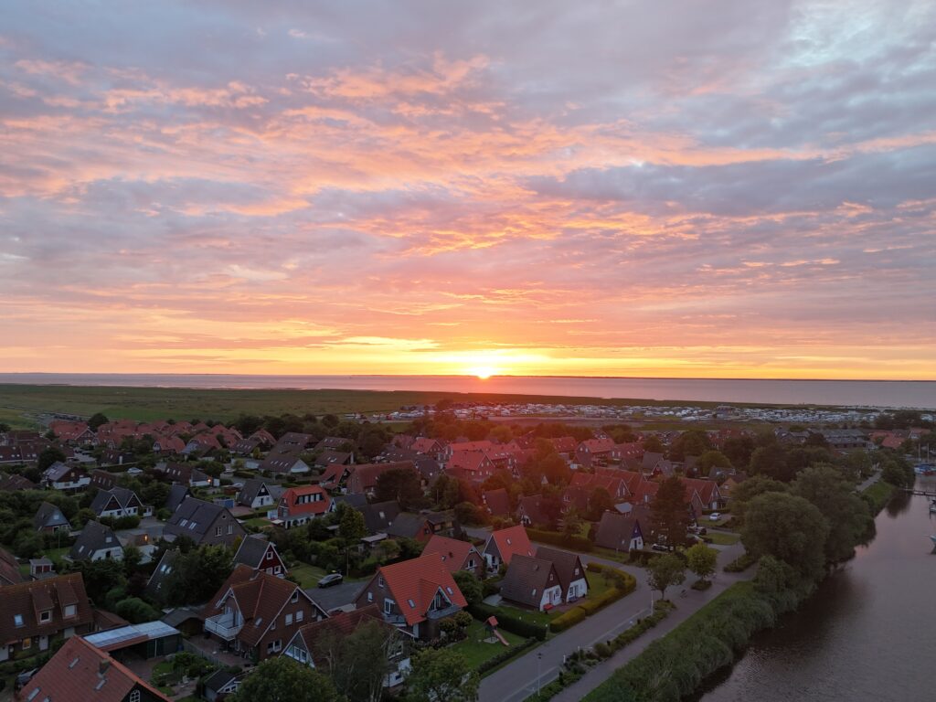 Luftbildaufnahme eines Sonnenuntergangs einer kleinen Hafenstadt am Meer